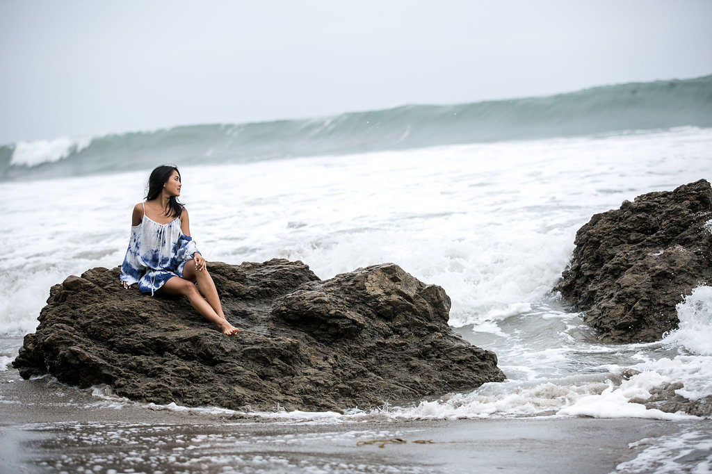 woman sitting on a rock at the beach and sharing her thoughts on positivity
