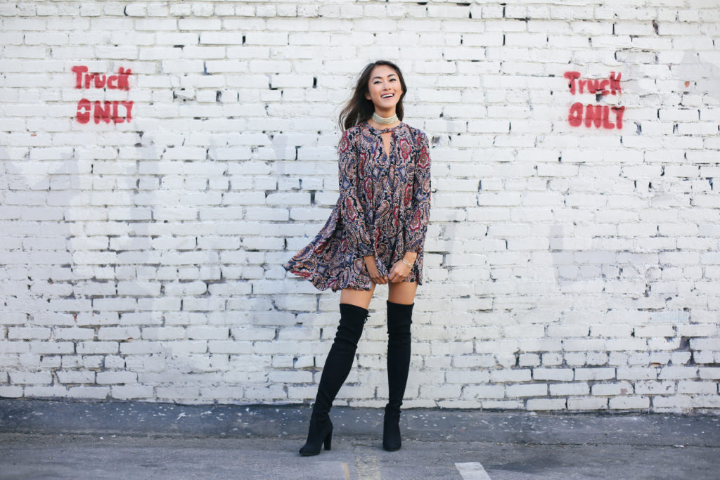 woman smiling and wearing Investment Pieces dress and knee high boots