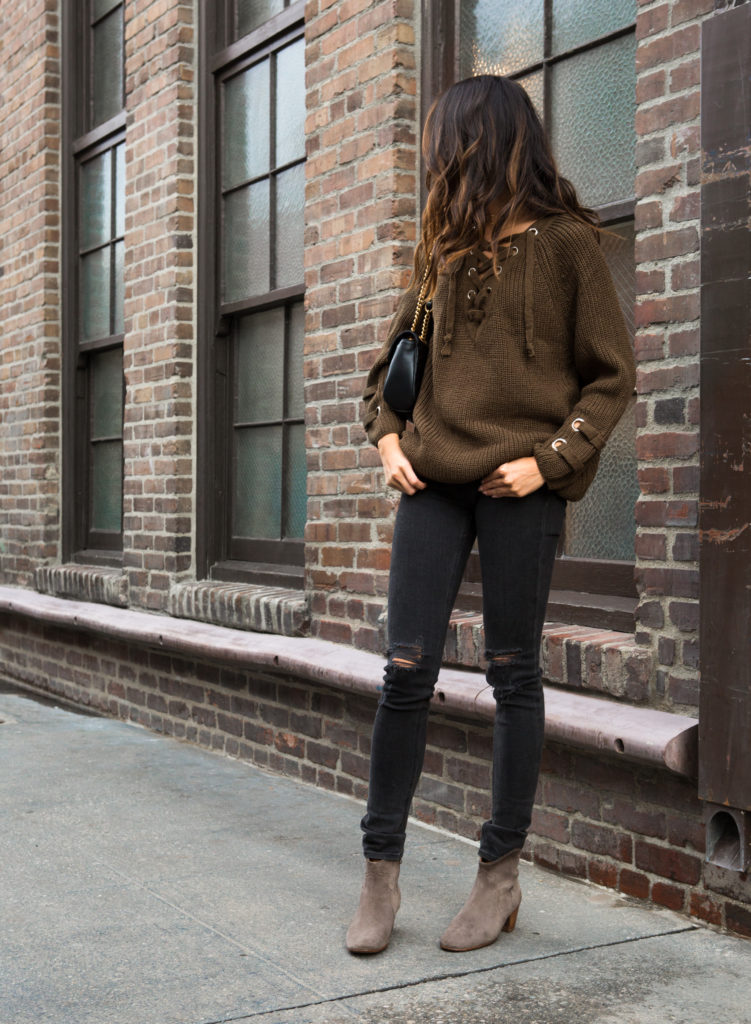 woman wearing one of the Lace Up Sweaters on brown and ripped denim jeans